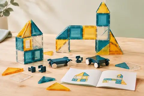 Tuiles magnétiques translucides assemblées en petites constructions sur un fond crème