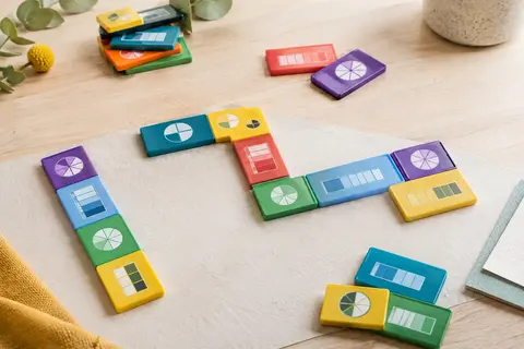 Dominos de fractions multicolores avec des représentations visuelles posés sur une table en bois clair.