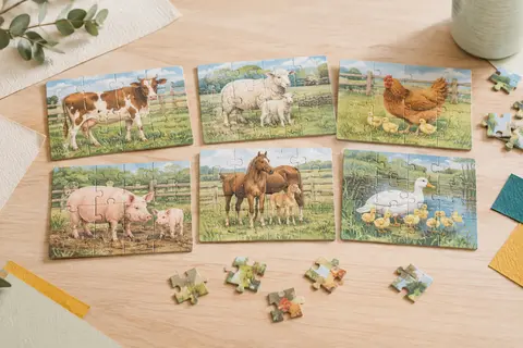 Six puzzles en carton épais sur le thème des animaux de la ferme, avec leurs pièces disposées sur une table claire.
