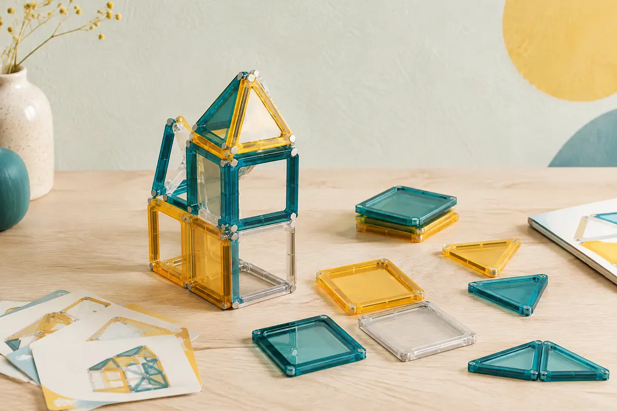 Pièces de construction magnétiques assemblées en petite structure sur une surface en bois clair