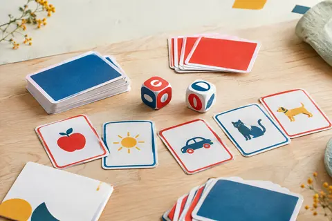 Deux dés-voyelles et des cartes de vocabulaire anglais bleu, rouge et blanc sur du bois clair