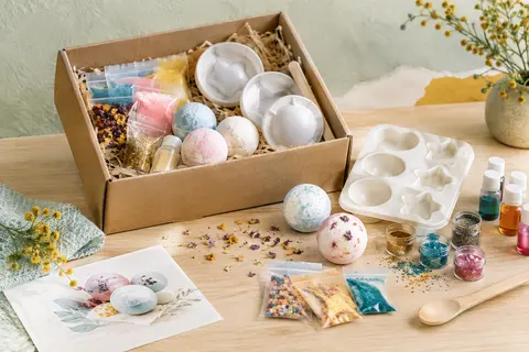 Coffret de fabrication de bombes de bain avec moules, éléments colorés et paillettes sur un fond clair